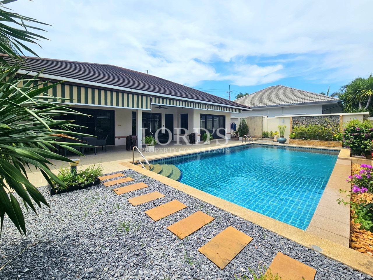 Luxury home with a private swimming pool, landscaped garden, and stone pathway