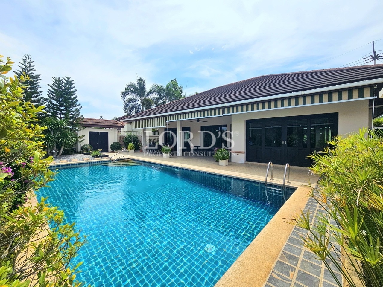 Luxury home with a large swimming pool, landscaped garden, and covered outdoor living area