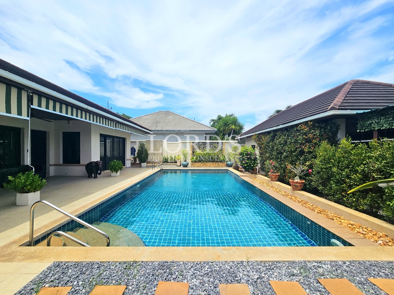 Large private swimming pool surrounded by tropical gardens and a spacious covered terrace