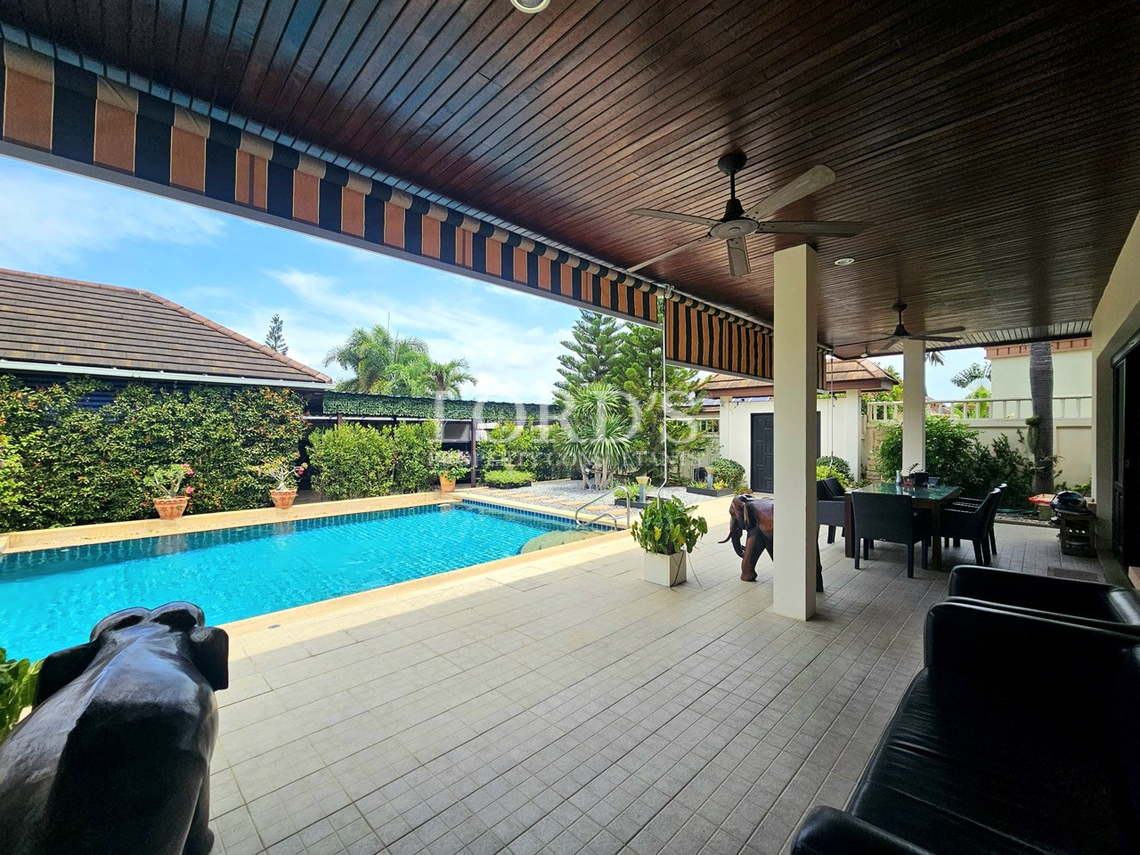 Covered poolside terrace with outdoor lounge and dining area overlooking a private swimming pool
