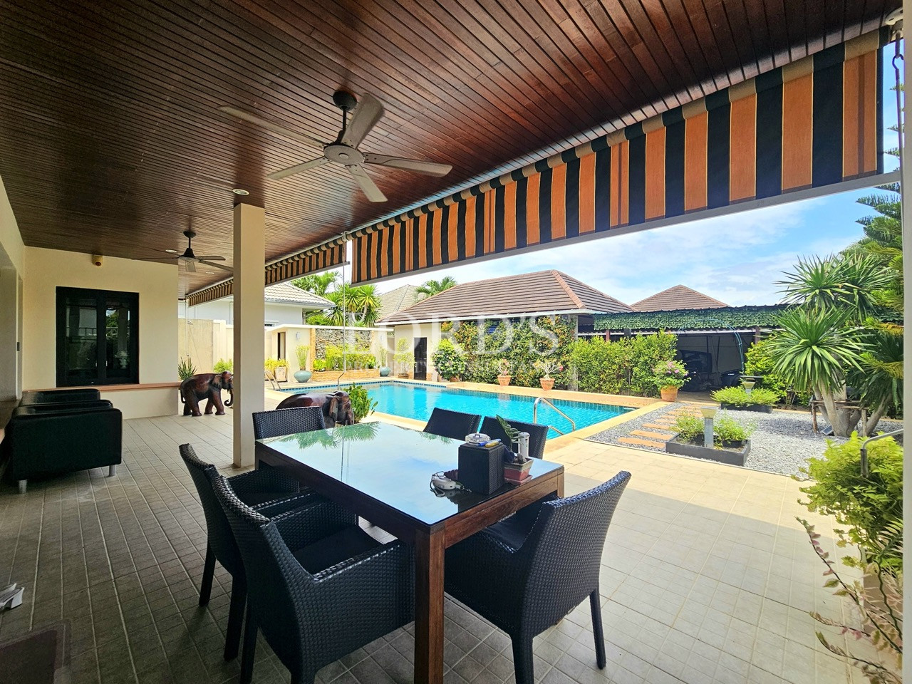 Covered outdoor dining terrace overlooking the private swimming pool and landscaped tropical garden