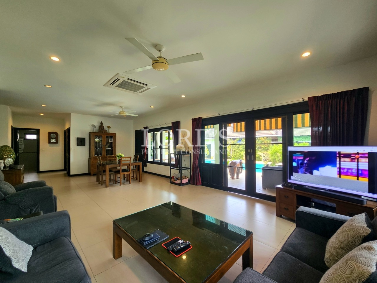 Spacious open-plan living room with large glass doors overlooking the pool and outdoor terrace