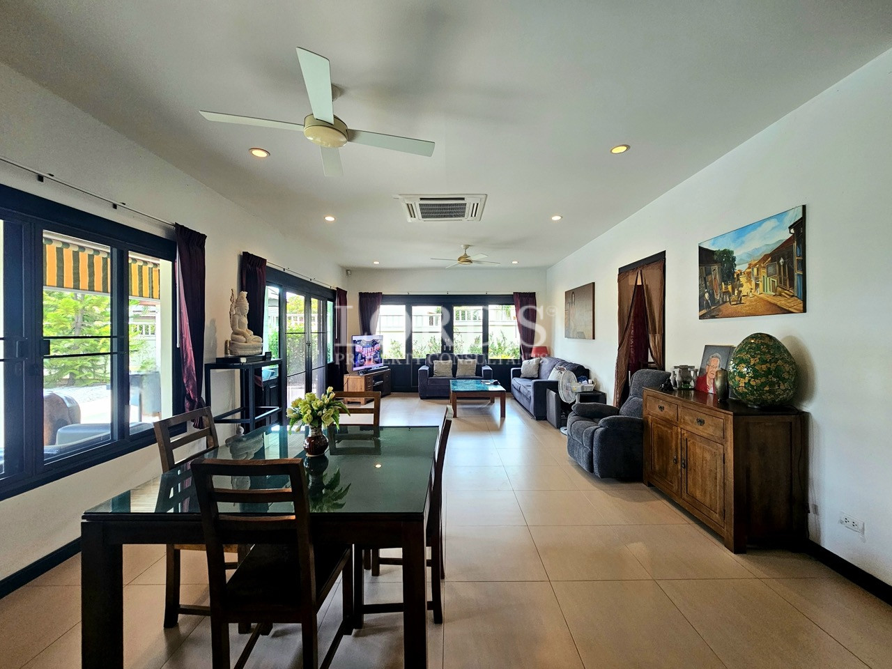 Bright open-plan living and dining room with large windows, comfortable seating, and garden views