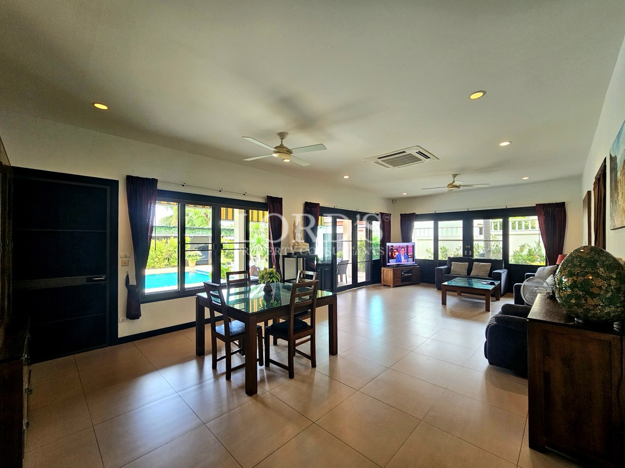 Open-plan living and dining area with pool views, large windows, and abundant natural light