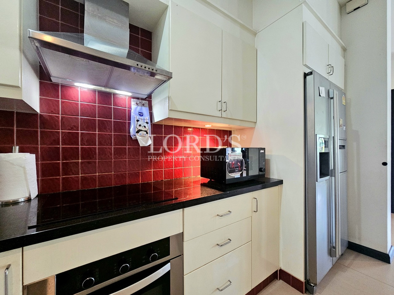 Modern kitchen with built-in oven, range hood, double-door refrigerator, and custom cabinetry
