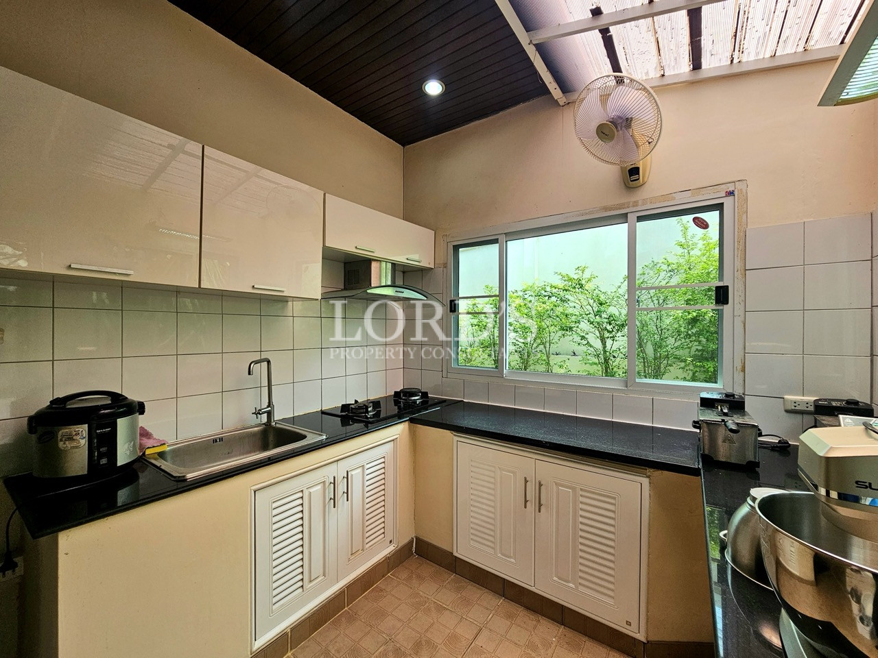 Functional service kitchen with black countertops, built-in cabinets, and large garden-view window