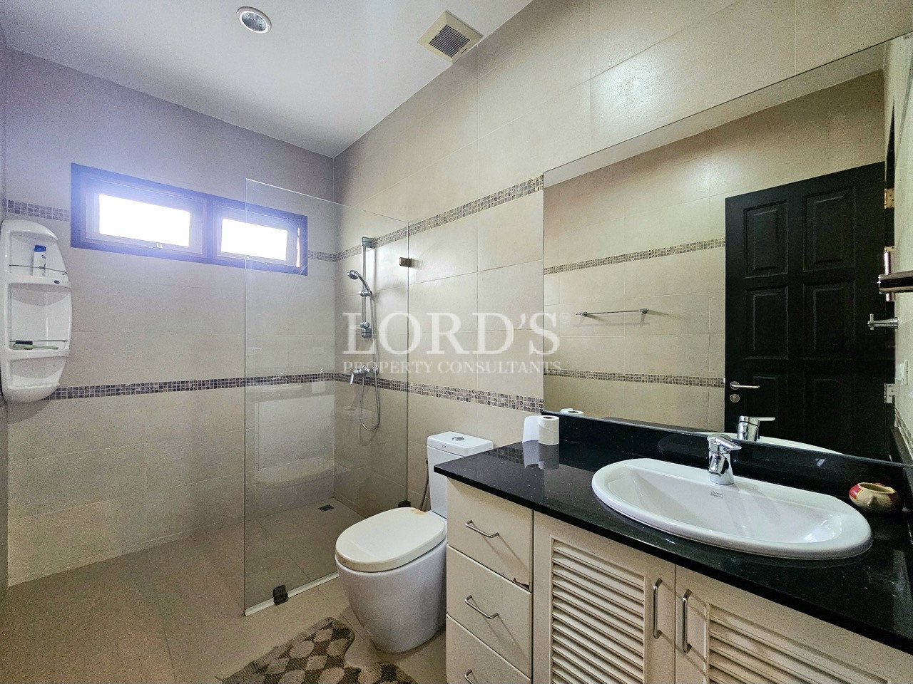 Contemporary bathroom with a walk-in glass shower, modern vanity, and neutral tiled interior