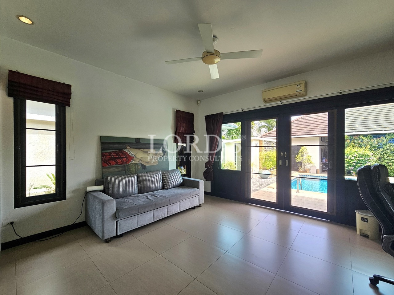 Bright multipurpose room with pool access, sofa, ceiling fan, and large glass doors
