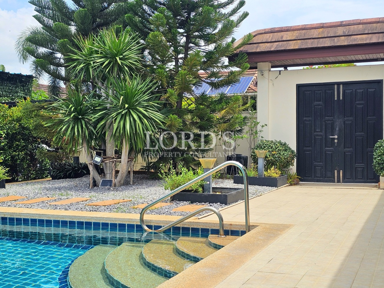 Private swimming pool entrance with curved steps, landscaped garden, and modern villa access