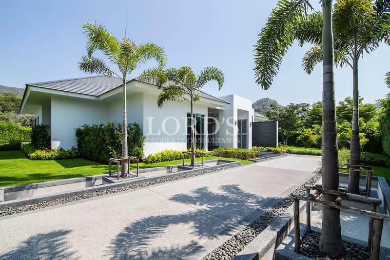 White luxury villa with landscaped lawn and tropical palm trees