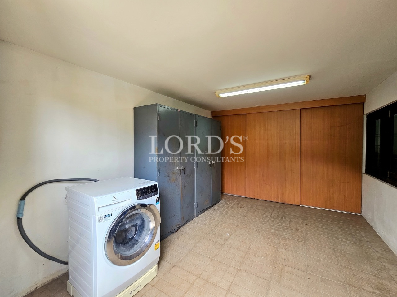Laundry and utility room with a front-loading washing machine, storage cabinets, and tiled flooring