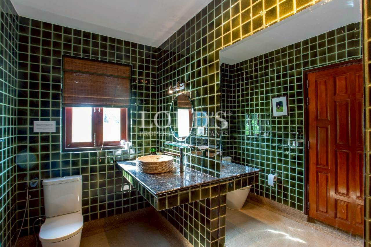 Luxury bathroom with green mosaic tiles and wooden vanity