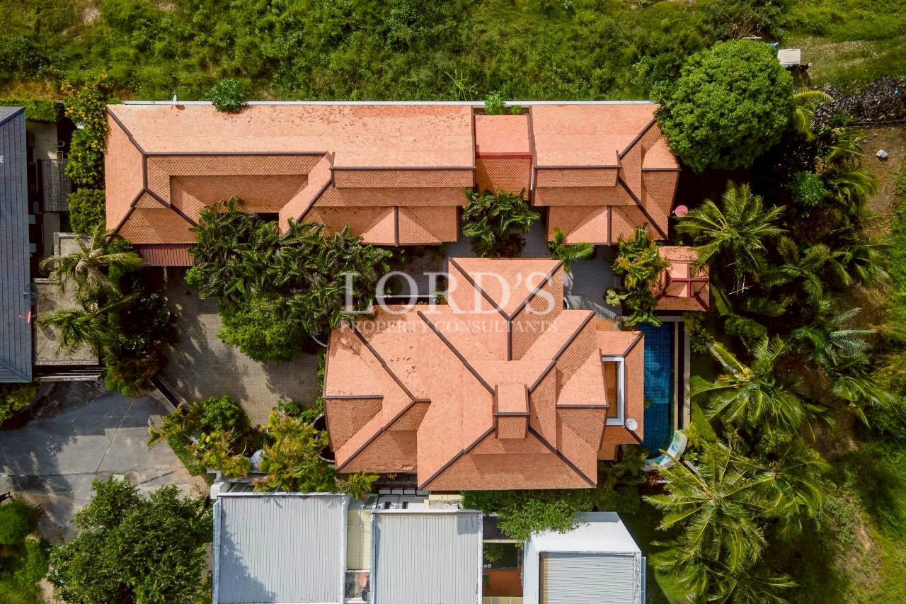 Drone view of luxury villas with red roofs surrounded by tropical greenery