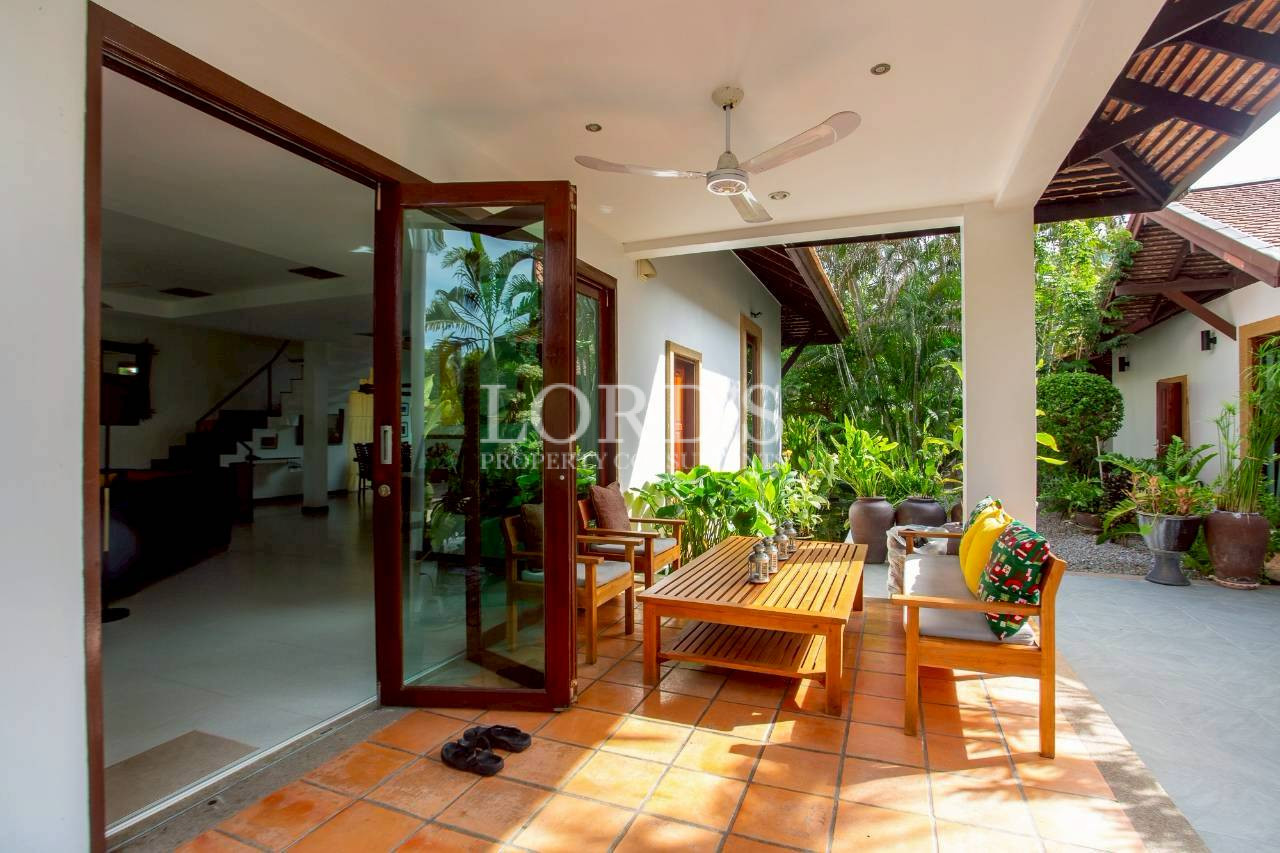 Open-air patio with wooden columns and tropical landscaping