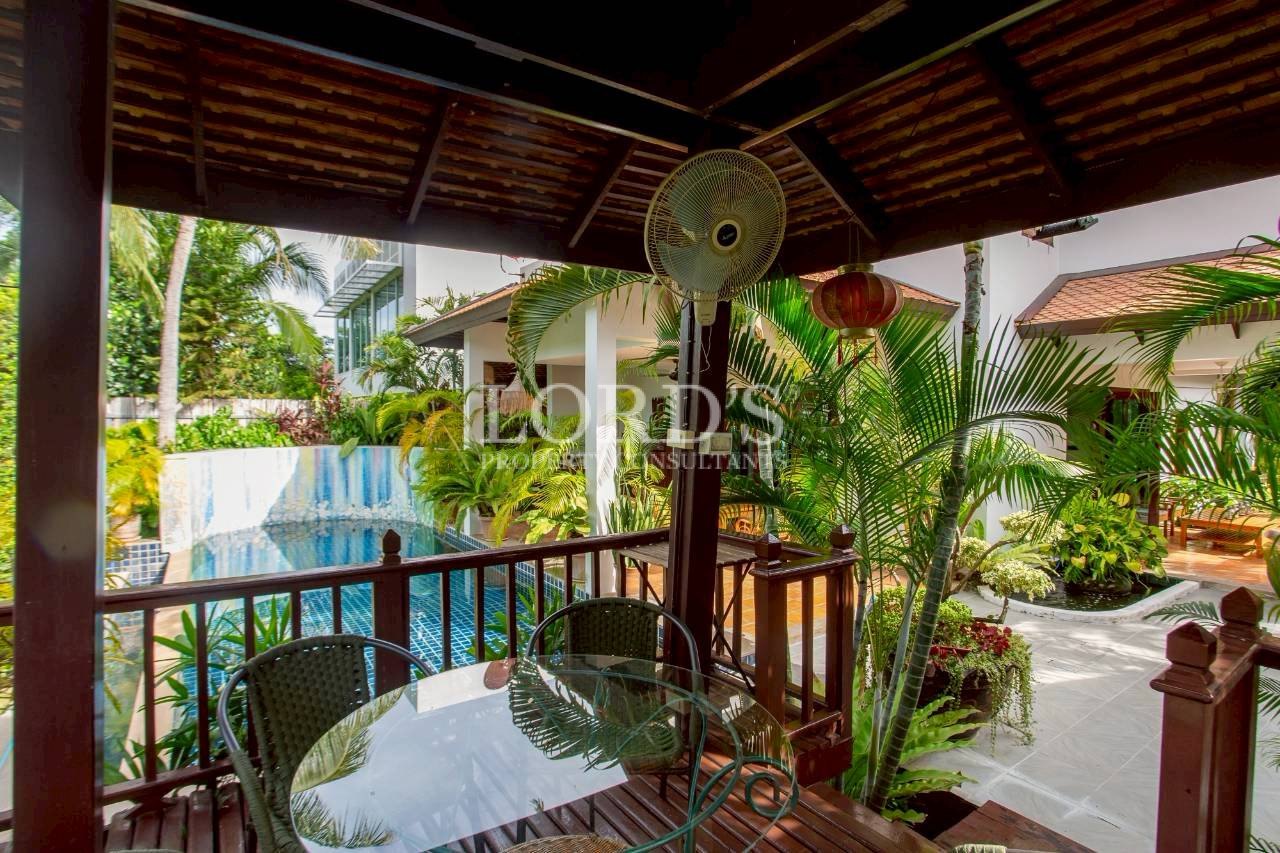 Covered outdoor lounge with wooden ceiling overlooking the pool