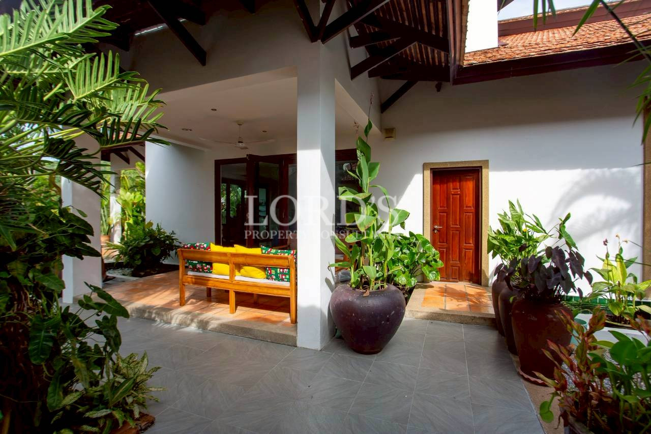 Modern villa entrance with tropical landscaping and covered porch