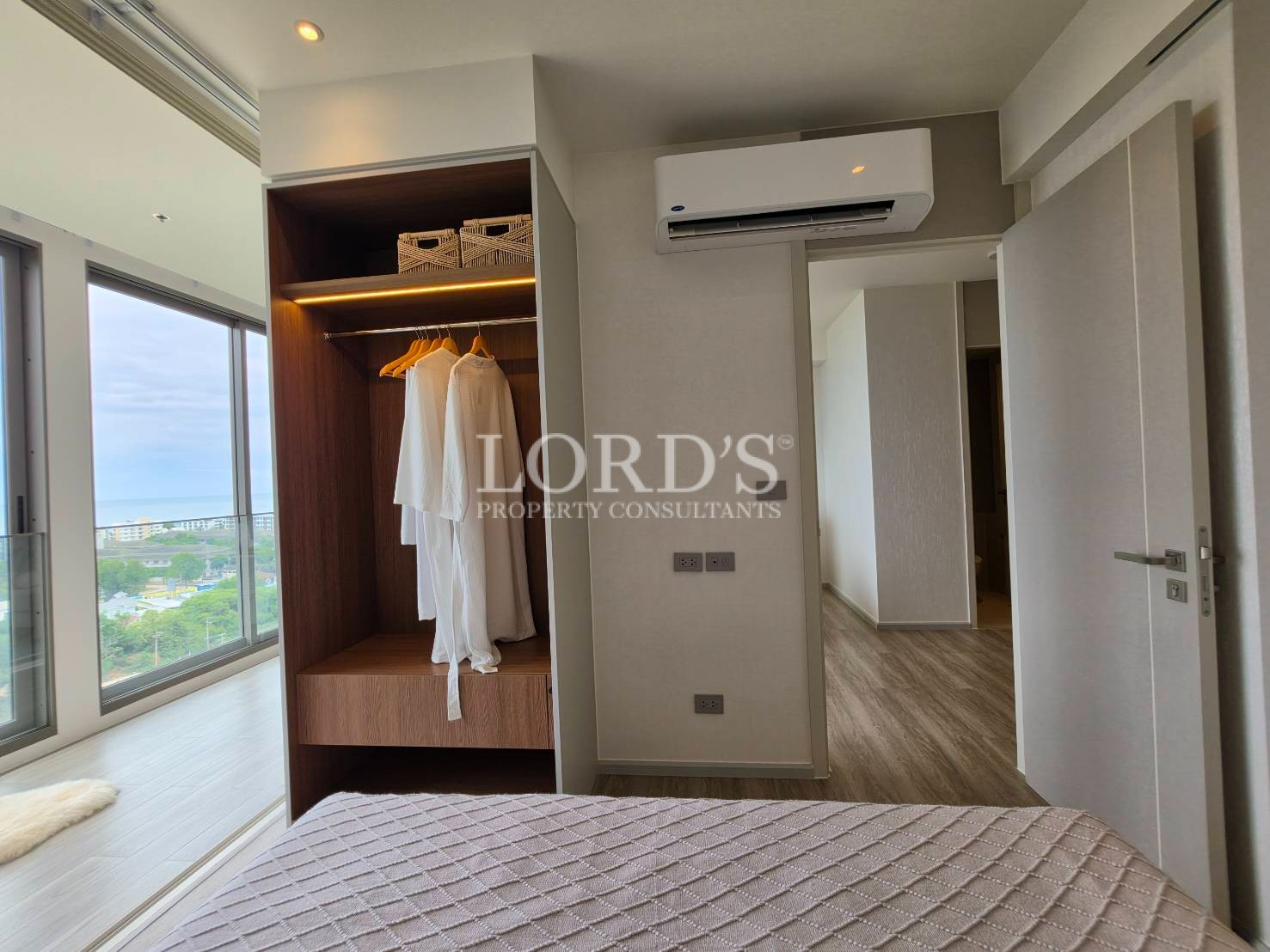 Modern bedroom with built-in wardrobe, air conditioner, and minimalist décor