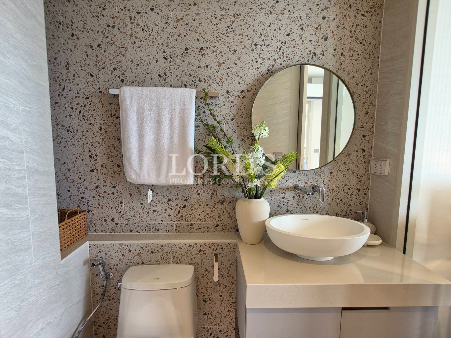 Modern bathroom with round mirror, textured stone wall, and floating vanity