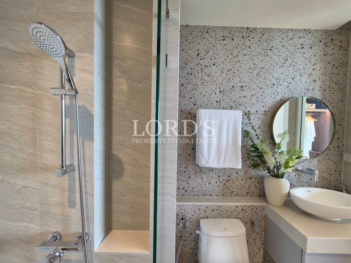 Contemporary bathroom with floating vanity, round mirror, and textured feature wall