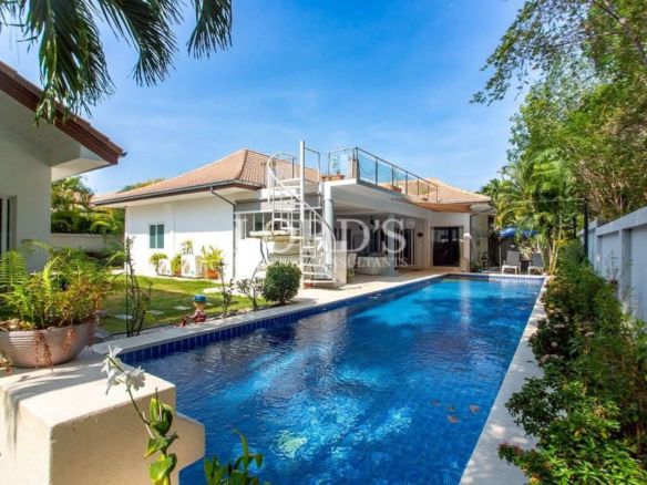 Luxury backyard swimming pool beside a modern white house