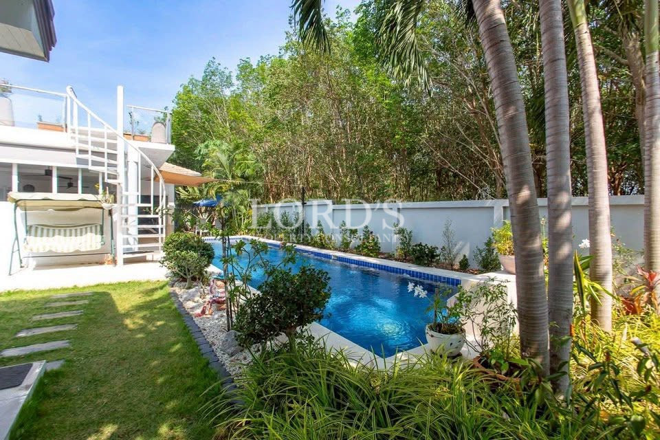 Tropical backyard with a swimming pool, palm trees, and landscaped garden