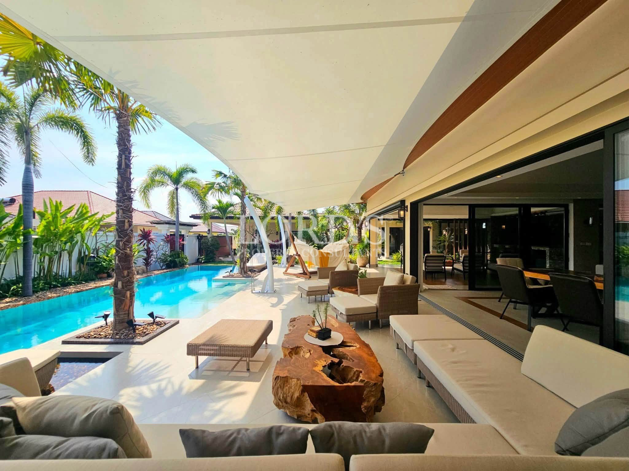 Luxury covered outdoor living area overlooking a tropical swimming pool and landscaped garden