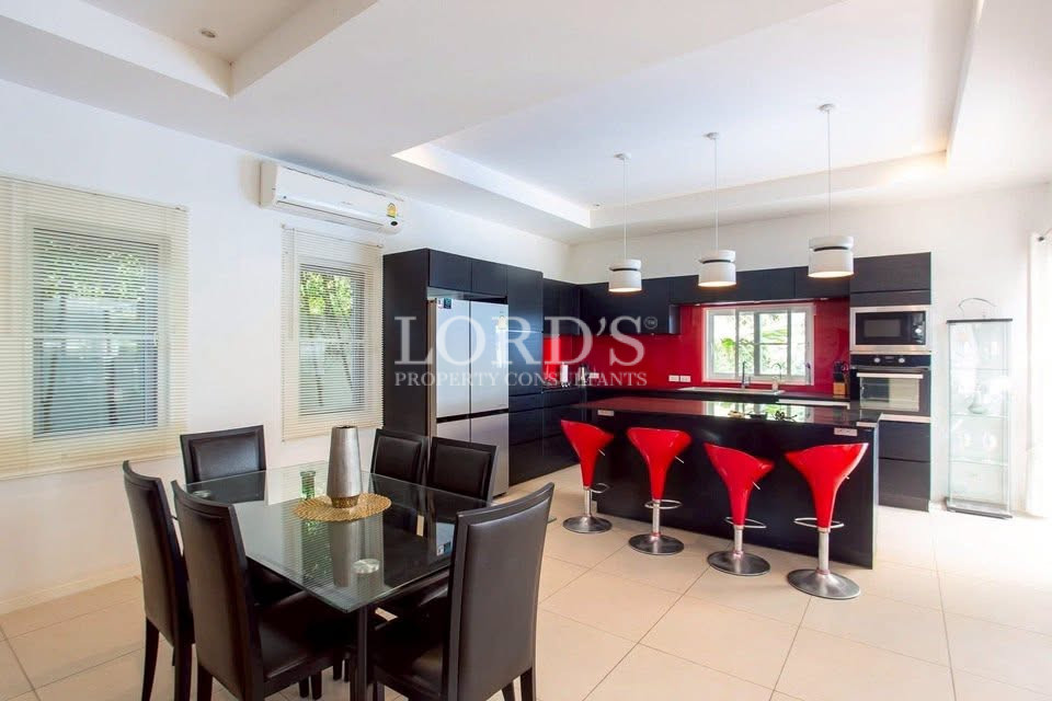 Modern open-plan kitchen and dining area with black cabinets and red bar stools