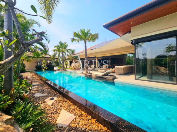 Luxury tropical villa with a long private swimming pool, sun loungers, and landscaped garden