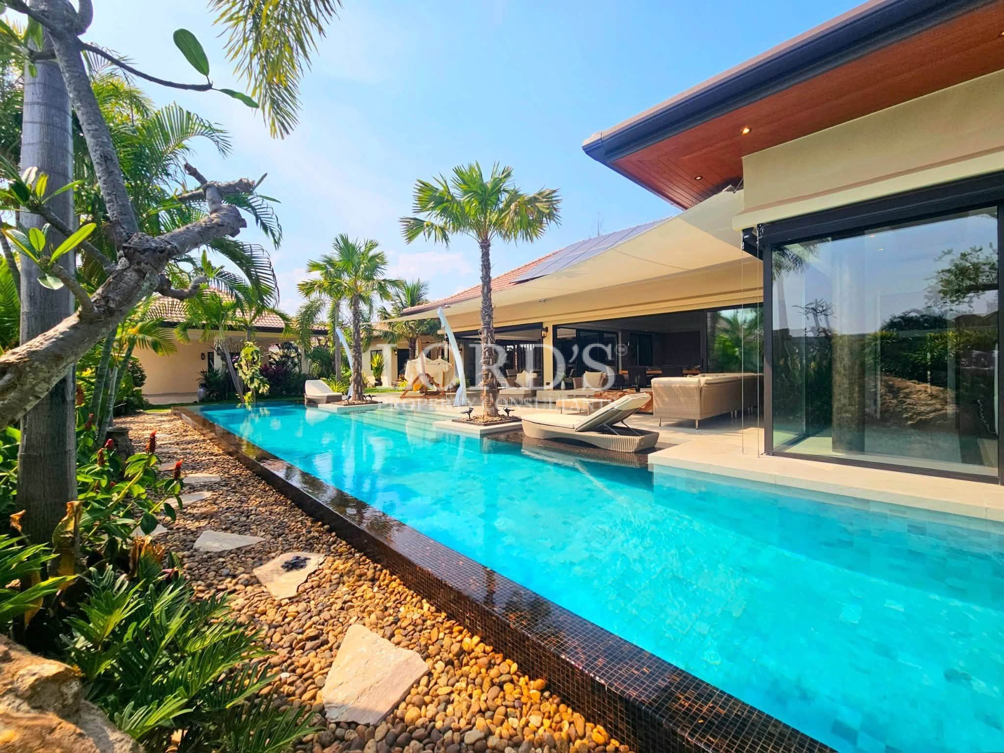 Luxury tropical villa with a long private swimming pool, sun loungers, and landscaped garden