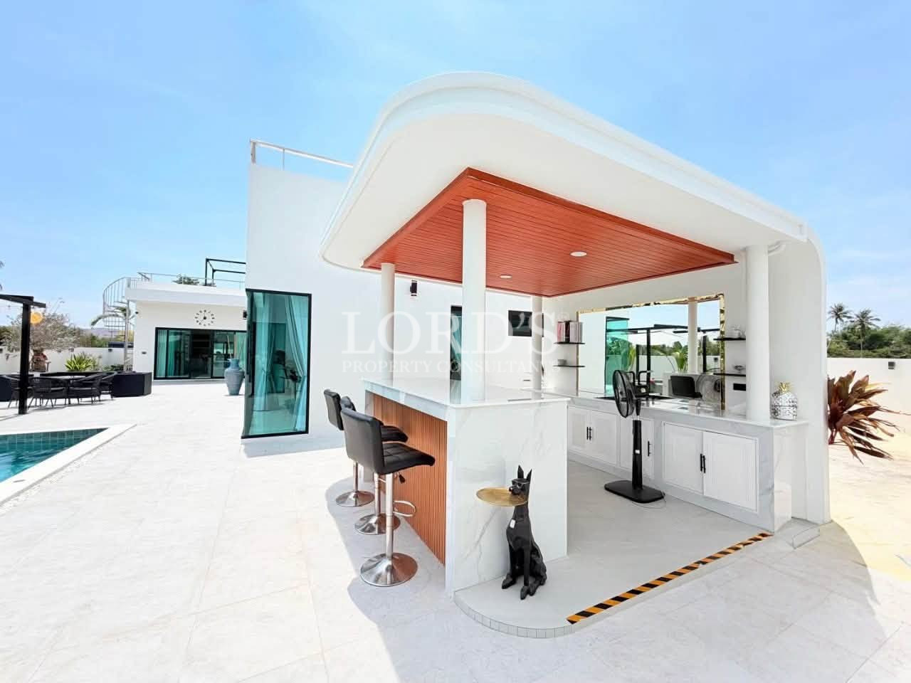 Modern outdoor poolside bar with a covered seating area and bar stools
