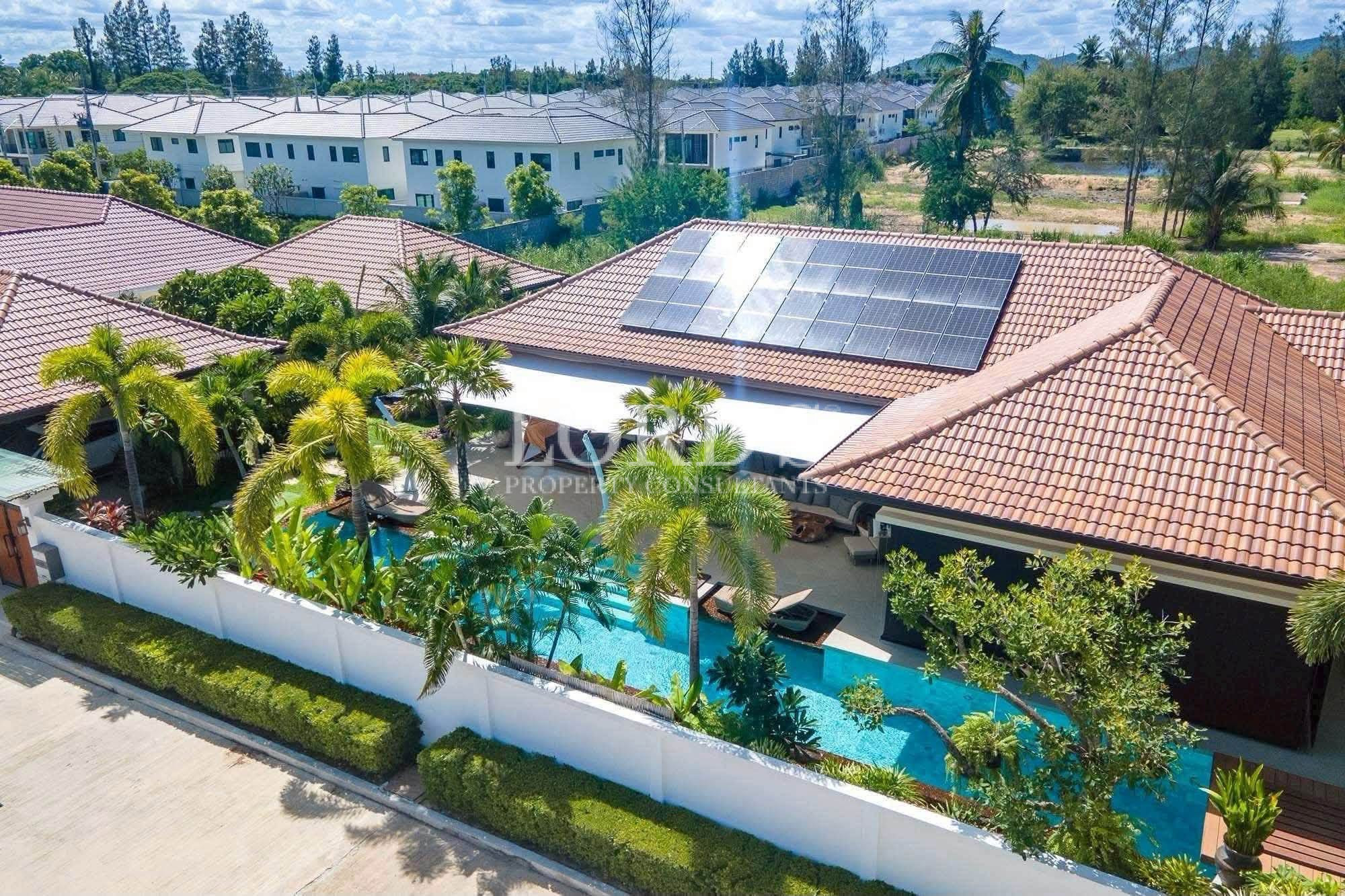 Aerial view of a luxury tropical villa with a private swimming pool, landscaped gardens, and rooftop solar panels