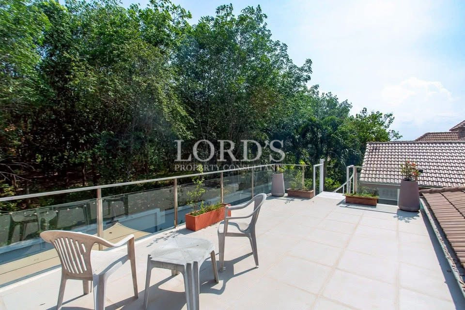 Spacious rooftop terrace with outdoor seating, glass railing, and views of surrounding greenery
