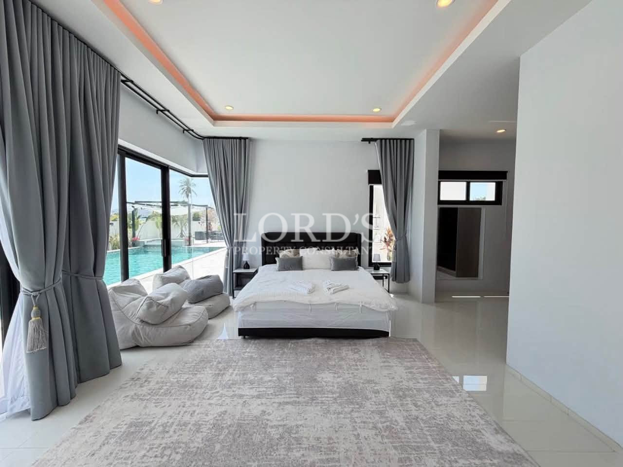 Modern luxury bedroom with a pool view, gray curtains, and a large area rug