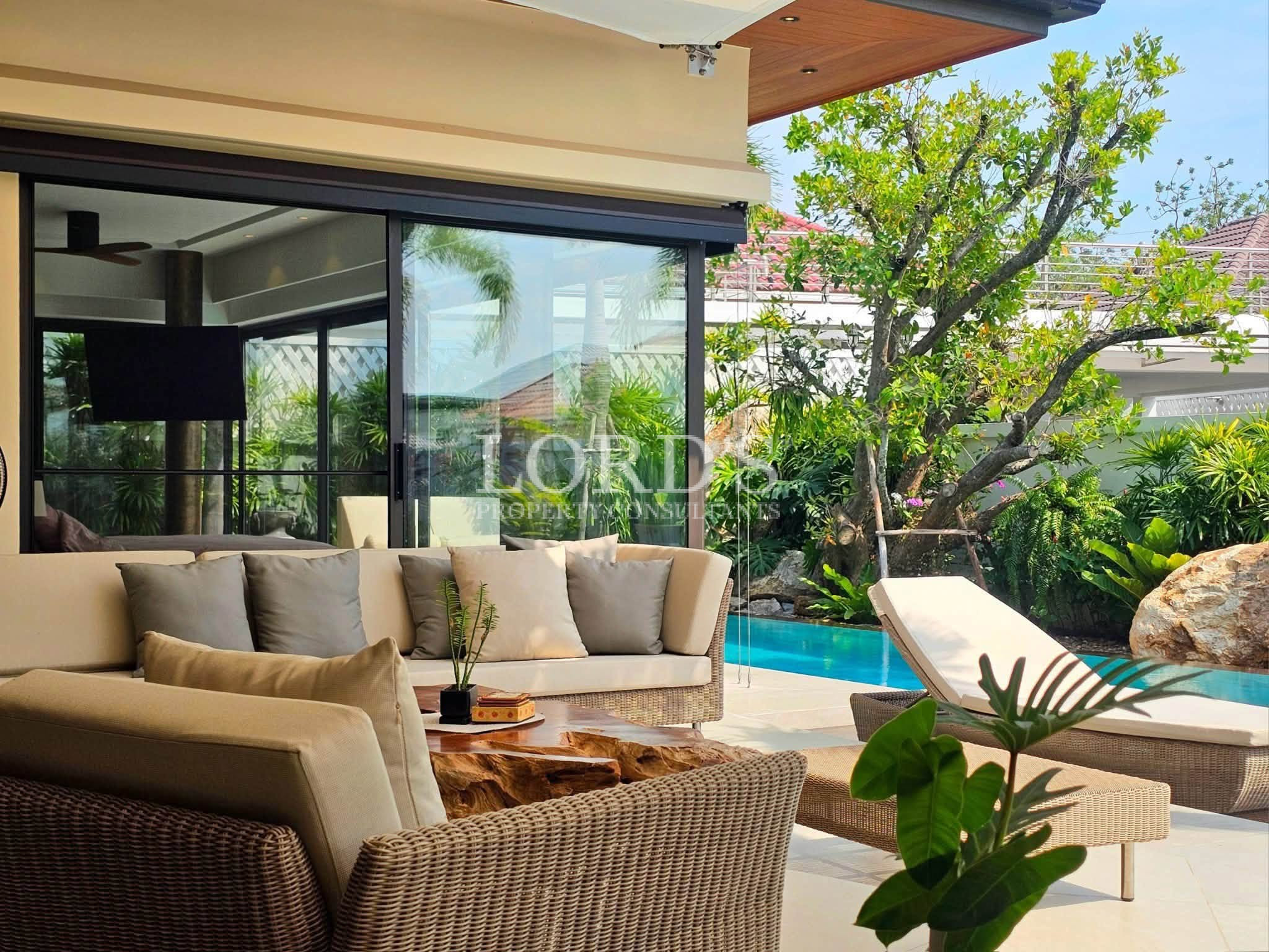 Luxury poolside patio with outdoor lounge seating, sun loungers, tropical garden, and private swimming pool