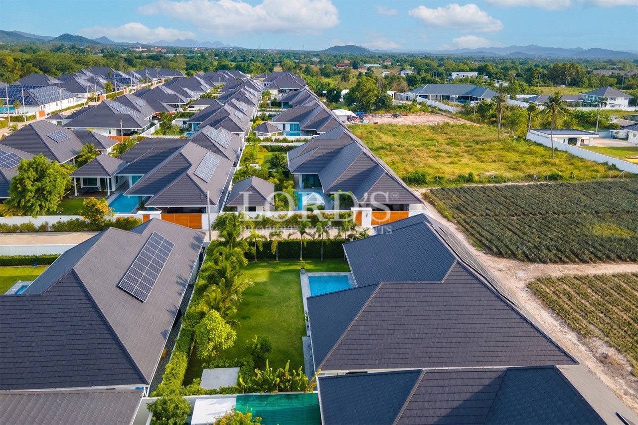 Aerial view of modern villas with private pools, solar panels, and landscaped gardens
