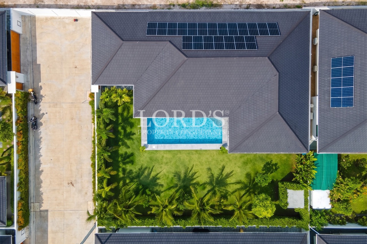 Aerial view of modern villa with private swimming pool, landscaped garden, and solar panels