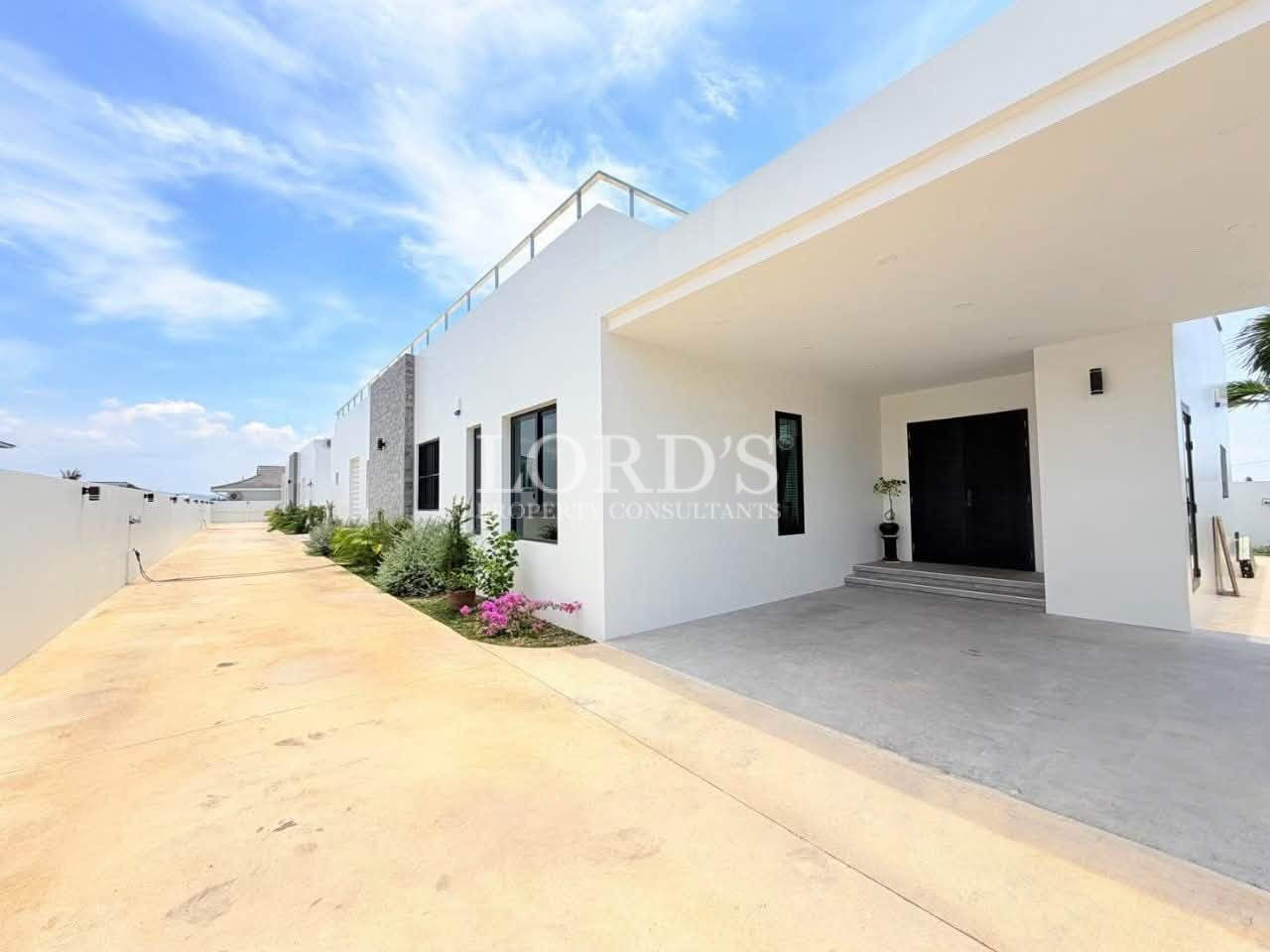 Modern luxury villa exterior with a covered carport and landscaped entrance