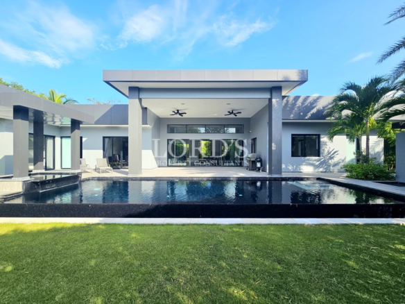 Luxury modern villa with a private swimming pool, covered outdoor patio, landscaped lawn, and contemporary architecture