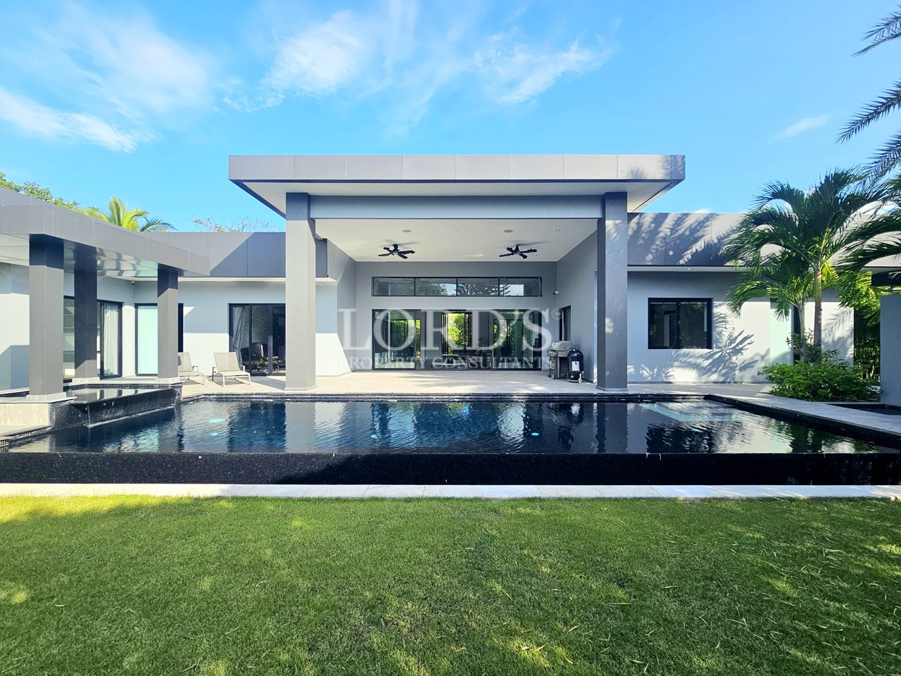 Luxury modern villa with a private swimming pool, covered outdoor patio, landscaped lawn, and contemporary architecture