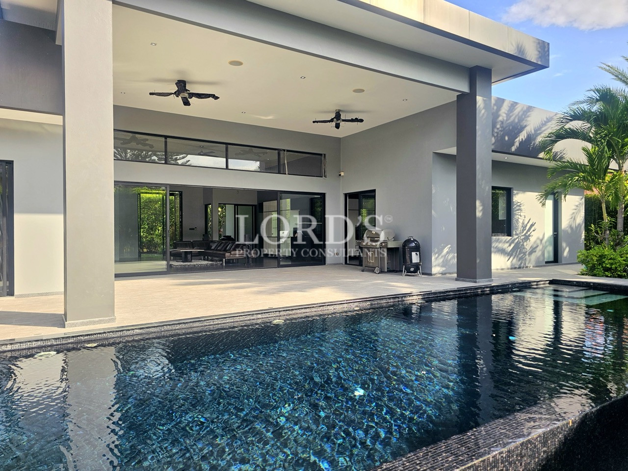 Luxury modern villa with private swimming pool, covered patio, floor-to-ceiling glass doors, and contemporary outdoor living area