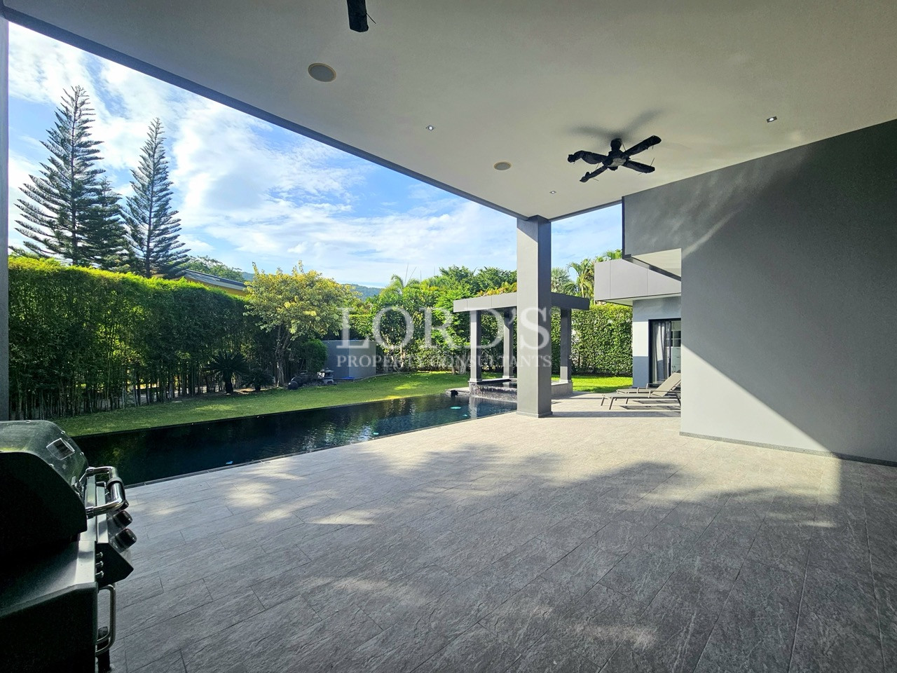 Luxury covered outdoor patio with private infinity-style swimming pool, landscaped garden, and modern villa architecture