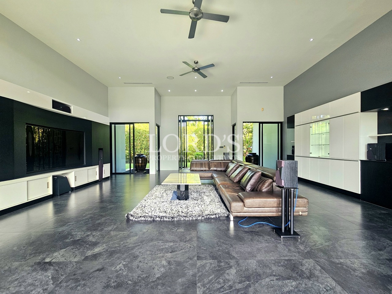 Luxury modern living room with high ceilings, contemporary sectional sofa, built-in entertainment wall, and open-concept design