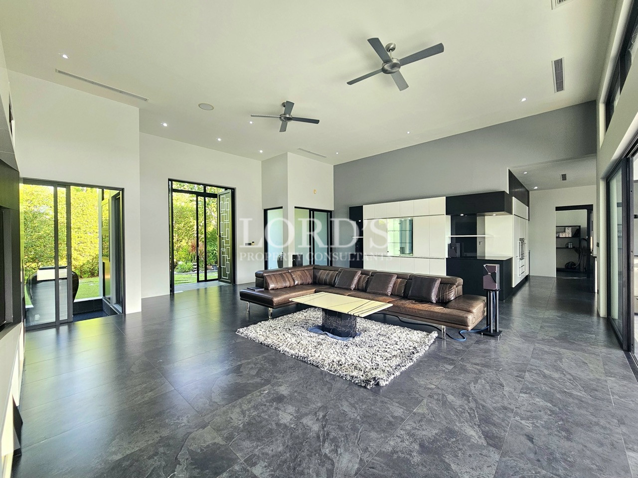 Modern luxury living room with high ceilings, open-concept layout, floor-to-ceiling windows, and contemporary furnishings