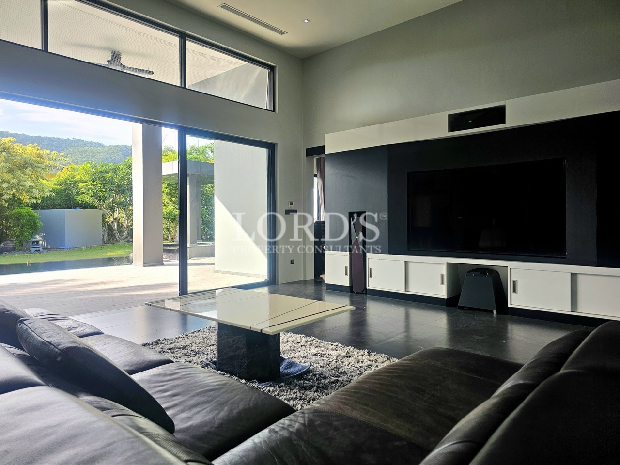 Luxury modern living room with home theater, floor-to-ceiling windows, and garden views