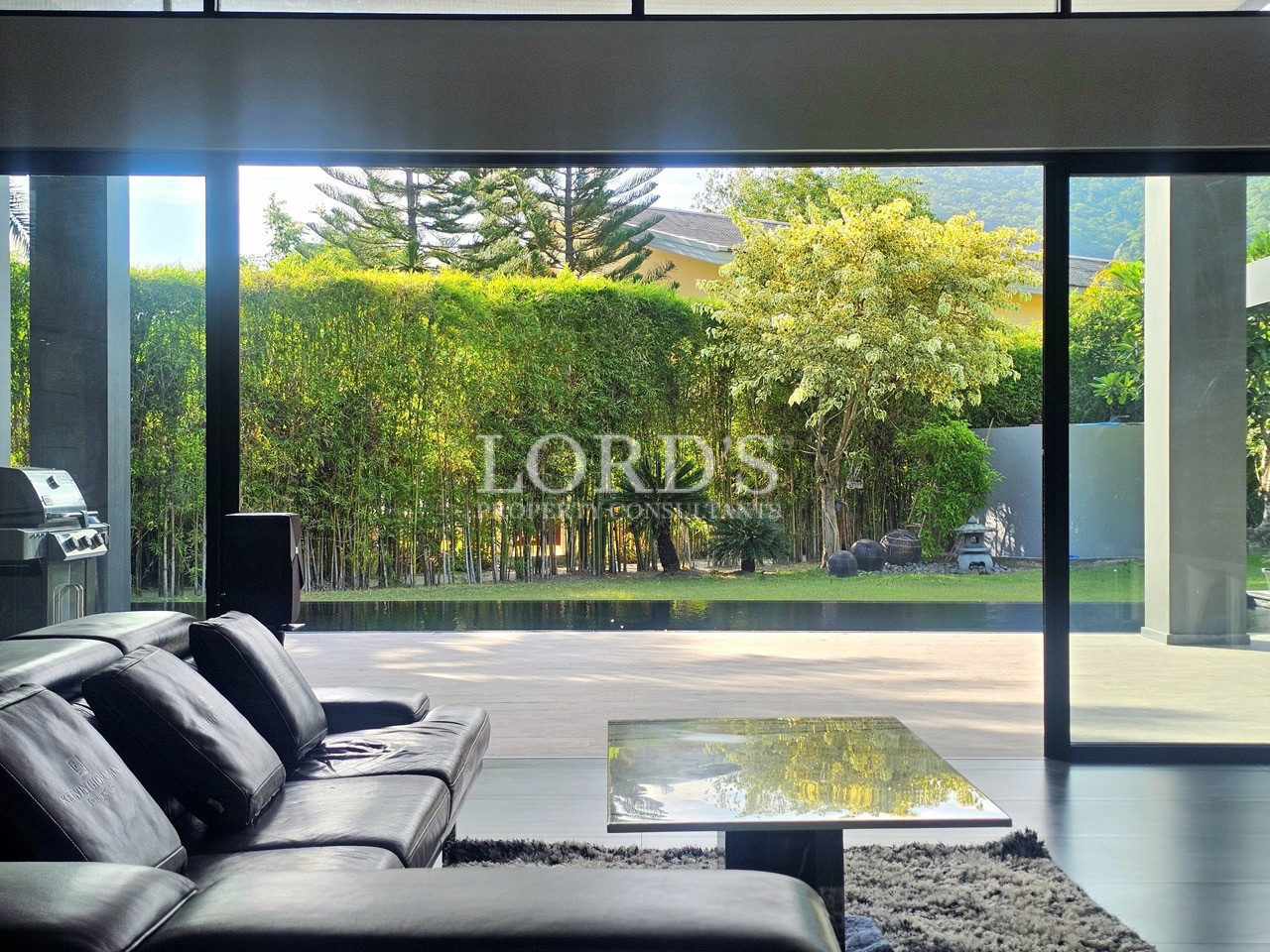 Modern living room with floor-to-ceiling glass doors overlooking a landscaped garden