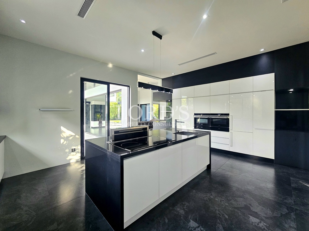 Modern luxury kitchen with black and white island, built-in appliances, and open-plan design