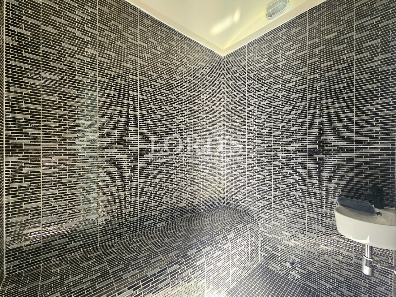 Luxury bathroom with black mosaic tiles and built-in shower bench