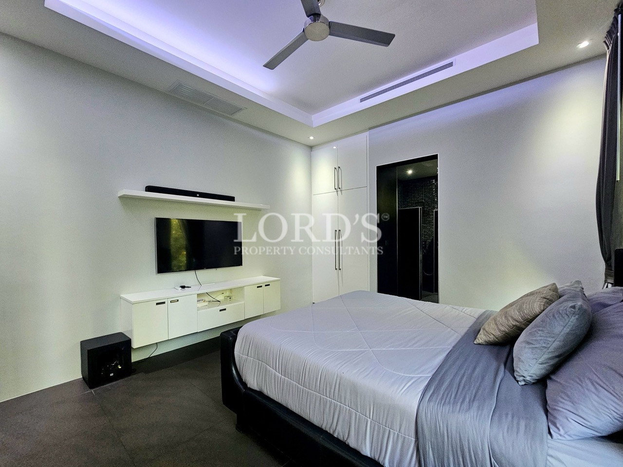 Modern master bedroom with wall-mounted TV and ensuite access