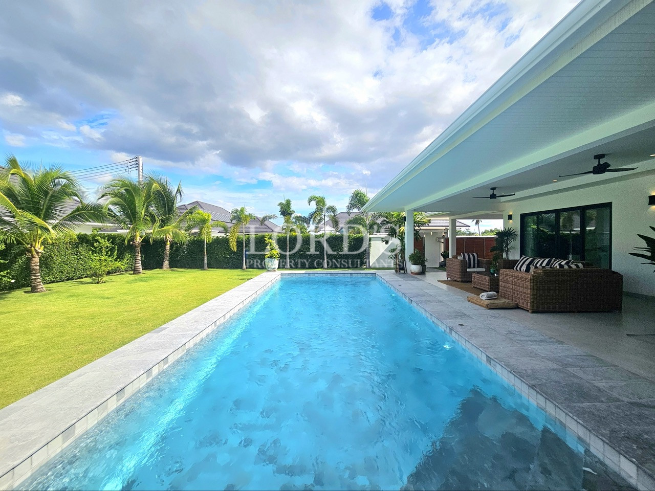 Modern backyard with swimming pool, tropical garden, and covered outdoor seating