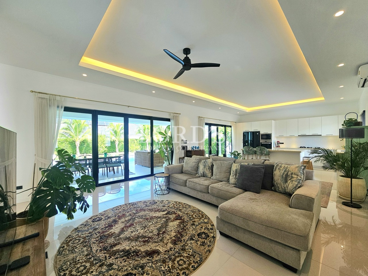 Modern living room and kitchen with sectional sofa, island, and garden views
